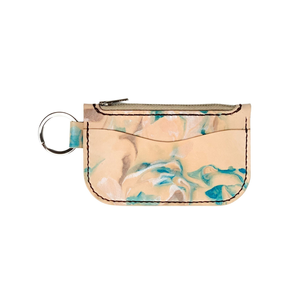 Front view of a leather key chain zipper wallet with one front pocket, one zipper pocket and a shiny nickel key ring attached.  Leather is a light natural color painted with water colors: brown, turquoise and and pearlescent white dyes.  Dark brown thread.